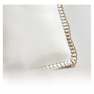 Macro shot of white lychee grain leather with woven chain edges and gold metal hardware