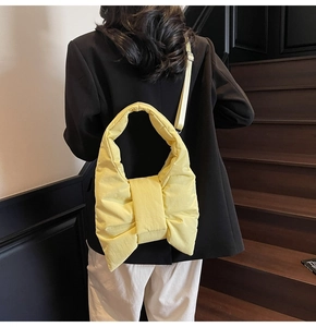 Detail view of yellow oversized bow quilted nylon tote bag worn on a model's shoulder