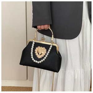 Detail of baroque black leather bag with gold heart emblem and white pearl chain