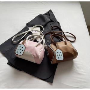 Flat lay of macaron-colored bowling handbags on a grey blazer showing detachable straps