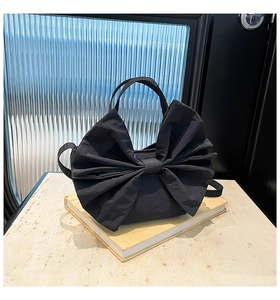 Détail du sac cabas à nœud noir avec bandoulière réglable sur fond esthétique vintage