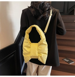 Detail of vibrant yellow puffer tote bag with a large bow design and adjustable strap