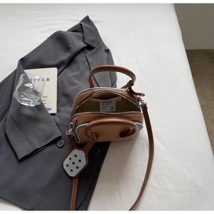 Detail view of brown leather handbag with contrast blue edges and adjustable shoulder strap