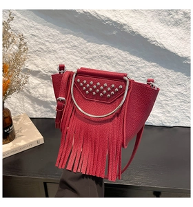 Detail of red pebbled leather bag featuring stylish fringes and silver stud accents