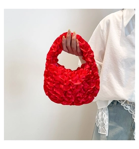 Detail showing the ruffled bright red satin handbag texture and floral folding design
