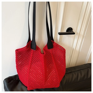 Close-up of red hollow crochet knit tote bag with black leather shoulder handles