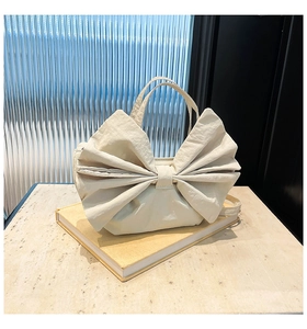 Détail du sac cabas beige à nœud avec texture gaufrée et bandoulière réglable