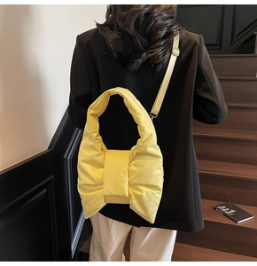 Detail of light yellow bow-shaped padded shoulder bag worn on black blazer outfit