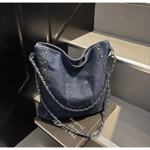 Detail of blue denim hobo bag featuring vintage bronze rivets and chain shoulder strap