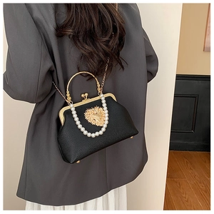 Detail of vintage black kiss-lock handbag with pearl chain and heart metal ornament