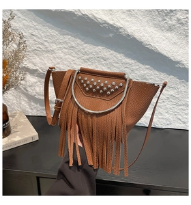 Close-up of brown lychee grain leather shell bag with rivets and tassel details
