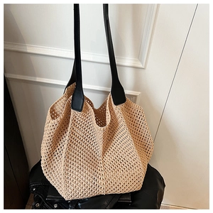 Detail of the woven mesh texture and leather straps on this large summer straw tote bag