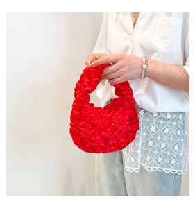 Detail of red pleated satin handbag with tiered ruffles and vibrant silk texture