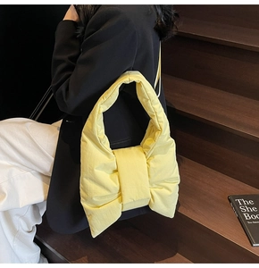 Close-up of a vibrant yellow quilted nylon handbag with a decorative bow design