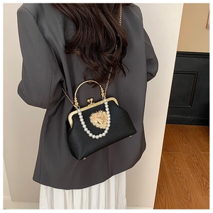 Baroque black leather bag with gold heart relief and pearl handle shown on model