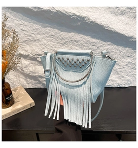 Detail of light blue crossbody shell bag featuring silver rivets and leather fringe tassels