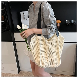 Lifestyle shot of an oversized woven tote bag with contrast black straps and mesh texture