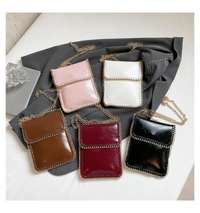 Close-up of small crossbody phone bags in five colors with metal chain trim and gold straps