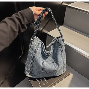 Detail of washed denim hobo bag featuring vintage copper studs and woven chain strap