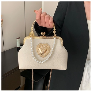 Detailed macro view of baroque frame handle and pearl chain on ivory evening bag