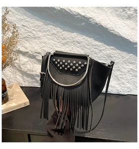 Detail of black pebbled leather crossbody bag with silver rivets, fringe and metal ring