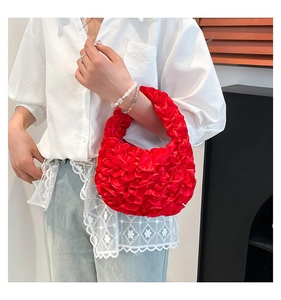 Detailed view of red ruffled satin handbag with elegant floral pleats and soft texture