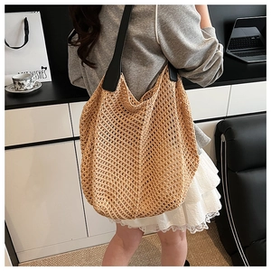 Detail of hand-woven tote bag with black leather strap and textured hobo design
