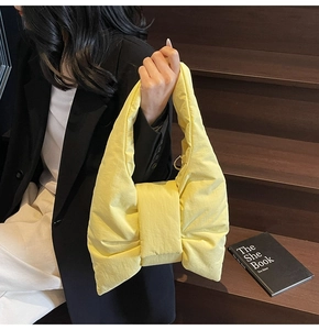 Detailed view of a bright yellow nylon tote bag featuring a large decorative bow design
