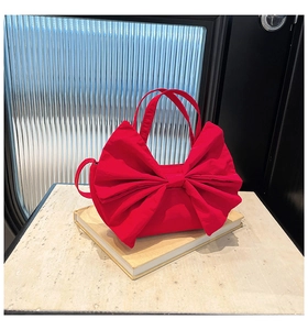 Gros plan détaillé d'un sac à main rouge en forme de nœud sur un livre avec sangle