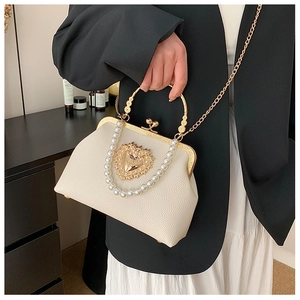 Detailed macro view of baroque cream leather handbag with gold heart and pearl chain