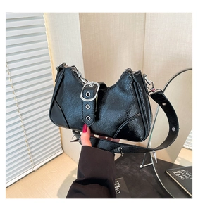 Détails des rivets argentés sur un sac à bandoulière en cuir verni noir au style moto