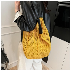 Close-up of bright yellow woven mesh tote bag with black leather shoulder strap