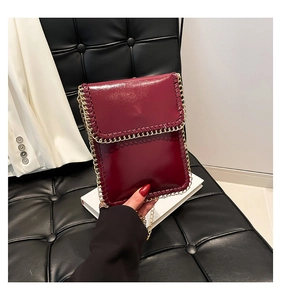 Close-up of wine red leather phone bag with woven chain edges and gold shoulder strap