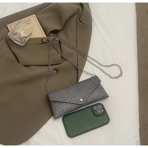 Detailed view of a grey textured mini envelope chain bag with white button and silver strap