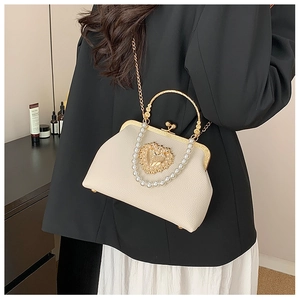 Close-up of cream white handbag with gold heart ornament, pearls and rhinestones