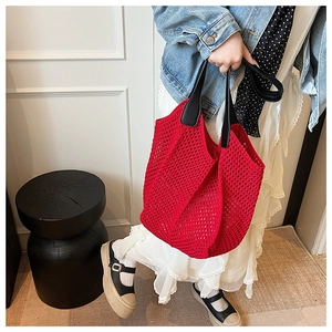 Detail of red hollow woven tote bag with black faux leather handles for women