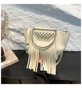 Close-up of beige lychee leather bag with bohemian tassels and silver rivet details
