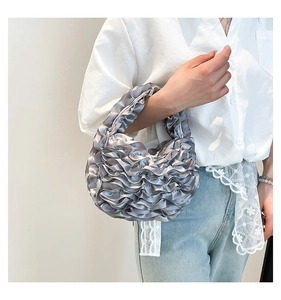Silver pleated cloud handbag worn by a model in casual attire for 2025 fashion style