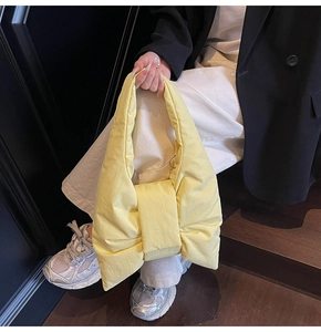 Detailed view of the yellow bow-shaped nylon shoulder bag worn by a female model