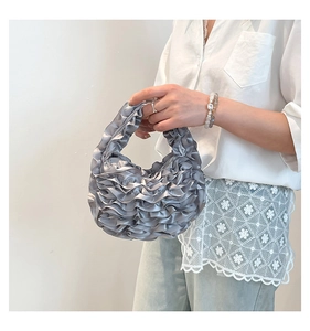 Detail of silver pleated satin handbag showing elegant layered texture and smooth finish