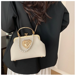 Close-up of beige lychee texture handbag with heart pearl clasp and golden chain
