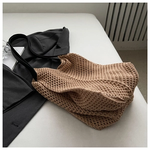 Detail of minimalist khaki knit tote bag showing intricate hollow crochet texture and strap
