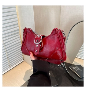 Détail d'un sac à bandoulière en cuir verni rouge avec boucle et clous métalliques