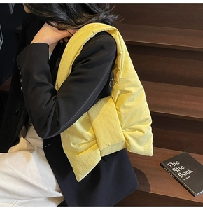 Detailed view of yellow puffy tote bag with oversized bow design worn by a model