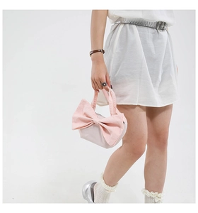 Sac fourre-tout en toile rose avec un grand nœud décoratif tenu par un mannequin