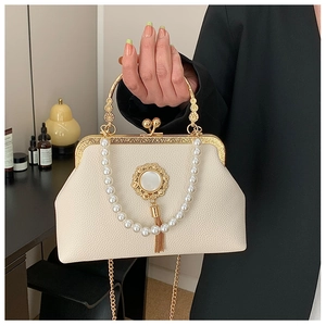 Close-up of Baroque style cream bag with gold floral pendant and pearl chain handle