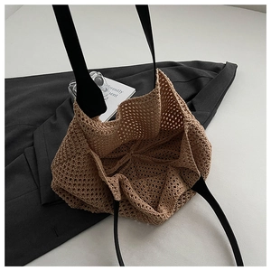 Detail of beige knit tote bag showing hollow mesh pattern and black shoulder strap texture