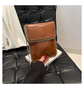 Detailed view of a brown faux leather mobile phone bag with golden chain trim and strap