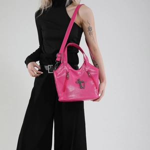 Pink punk tote bag with cross pendant and adjustable shoulder strap worn by model