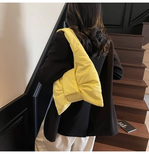 Model wearing a bright yellow oversized nylon bow shoulder bag with a black blazer